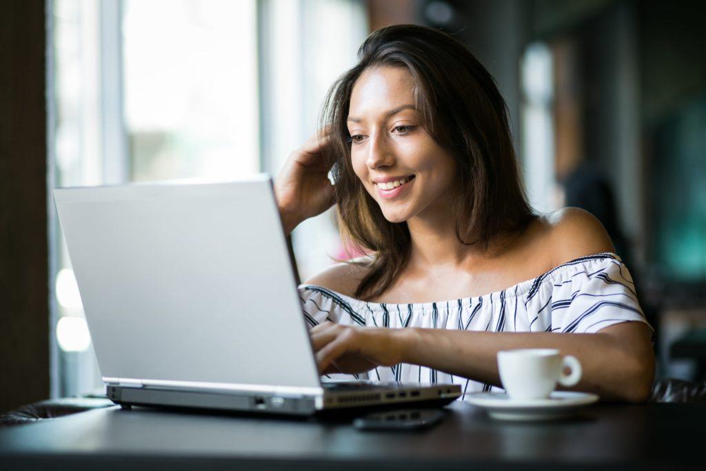 年轻女子在电脑前喝咖啡